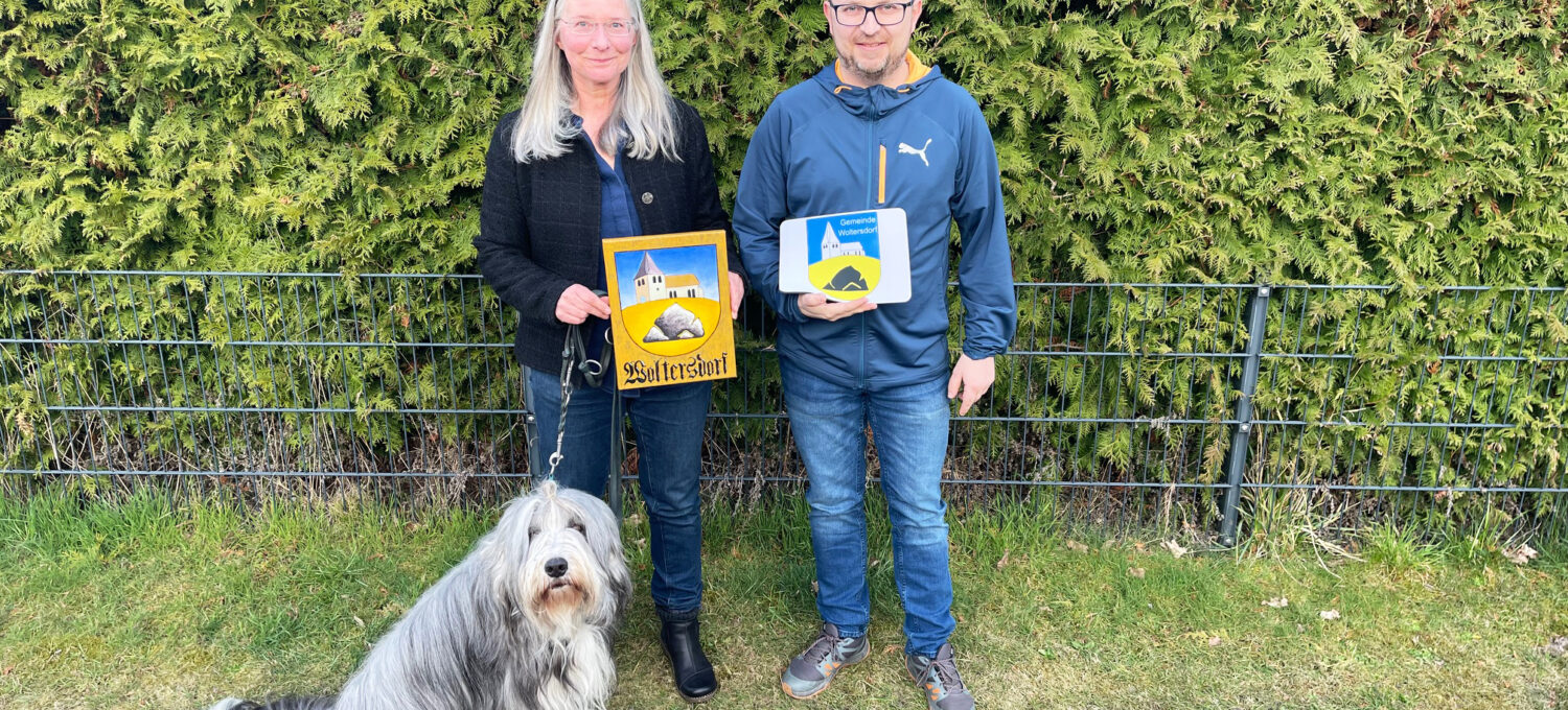 Ina Baumbach mit ihrem Hund Floyd und Woltersdorfs Bürgermeister Tobias Gauster mit den offiziellen Wappen von Woltersdorf.