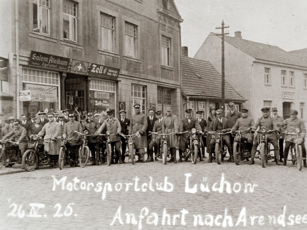 Im Mai unternehmen viele eine MAitour - schon vor 100 Jahren: Ausfahrt des Motorsportclub Lüchow 1925 nach Arendsee. Im Gebäude hinter der Gruppe befindet sich die Sanitätsdrogerie von Paul Hilberg.
