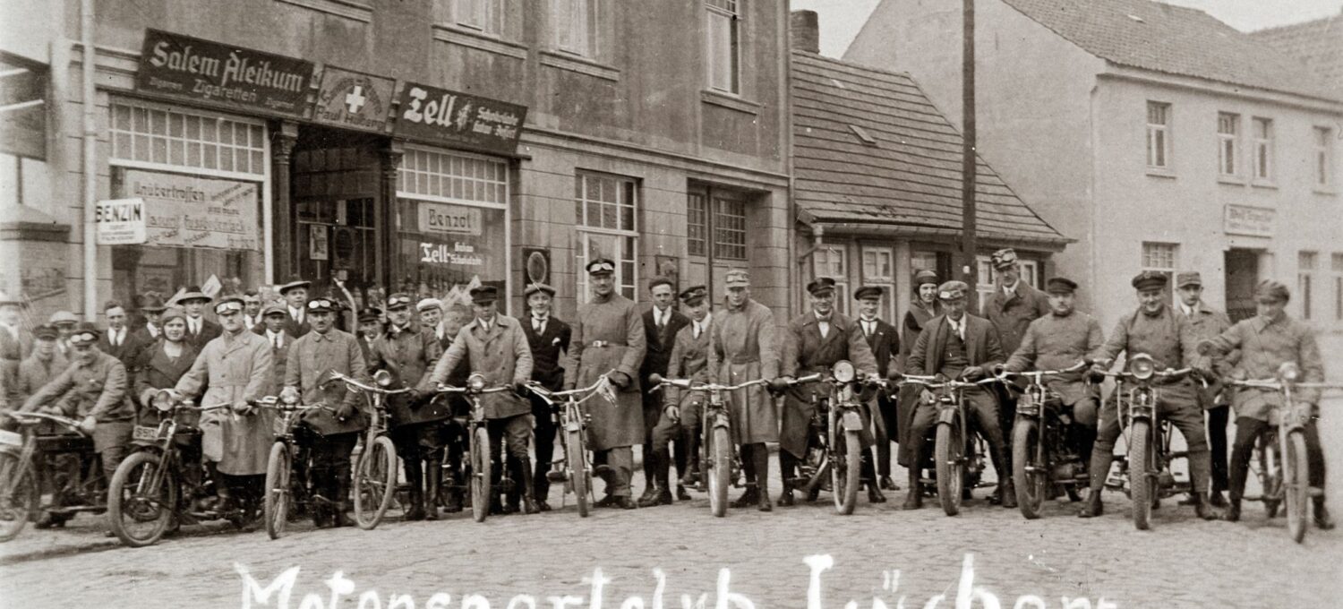 Im Mai unternehmen viele eine MAitour - schon vor 100 Jahren: Ausfahrt des Motorsportclub Lüchow 1925 nach Arendsee. Im Gebäude hinter der Gruppe befindet sich die Sanitätsdrogerie von Paul Hilberg.