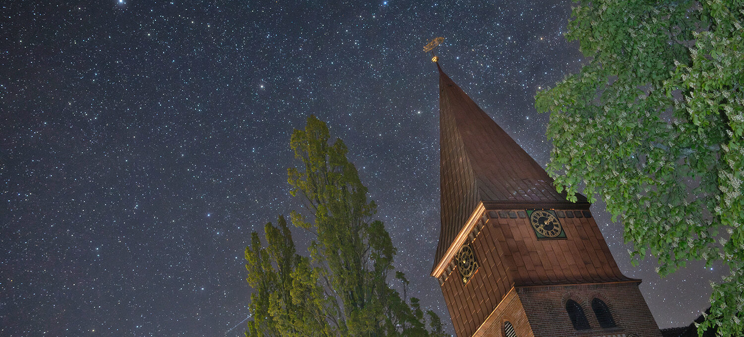 nach aufwendiger Renovierung erstrahlt die Michaeliskirche von Schnega
jetzt wieder in neuem Glanz.  Meine Aufnahme ist gestern Morgen um 02:12 Uhr entstanden. Links oben
ist der Polarstern zu sehen. Das Sternbild Cepheus erstreckt sich über
den gesamten übrigen Himmelsbereich. Schon bei mittlerer Bildschirmgröße
ist rechts am Kastanienlaub Herschels Granatstern mit seinem auffällig
rötlichen Schimmer erkennbar.
