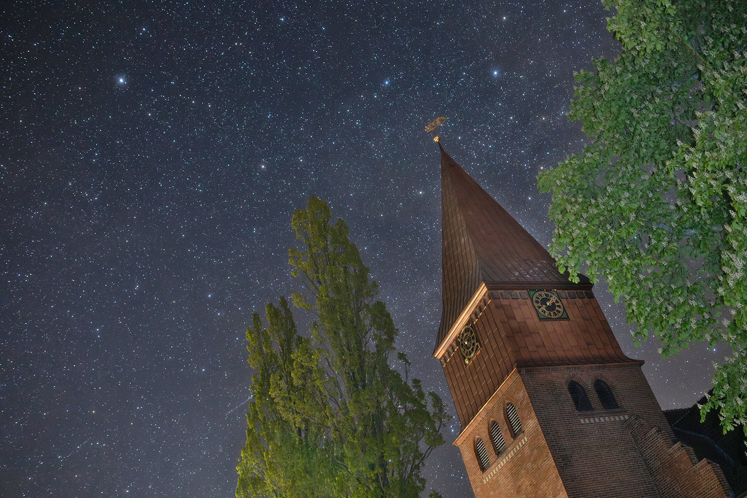 nach aufwendiger Renovierung erstrahlt die Michaeliskirche von Schnega
jetzt wieder in neuem Glanz.  Meine Aufnahme ist gestern Morgen um 02:12 Uhr entstanden. Links oben
ist der Polarstern zu sehen. Das Sternbild Cepheus erstreckt sich über
den gesamten übrigen Himmelsbereich. Schon bei mittlerer Bildschirmgröße
ist rechts am Kastanienlaub Herschels Granatstern mit seinem auffällig
rötlichen Schimmer erkennbar.