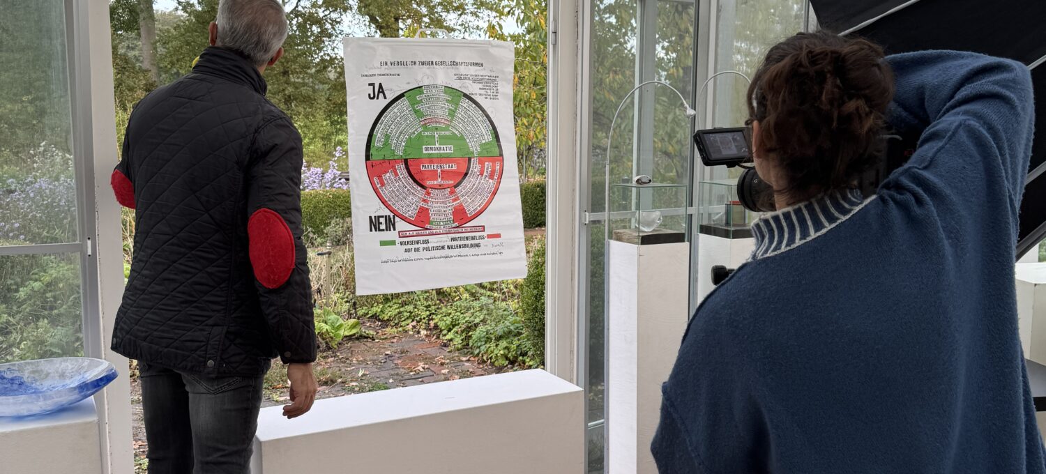 Anaisio Guedes (links) von "Bares für Rares" fotografiert in Groß Heide während der Sendung die von Sybille Homann gestaltete Vitrine mit dem Kunstwerk von Joseph Beuys. Foto: S. Homann