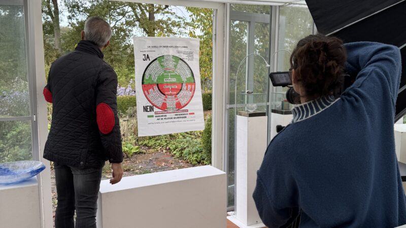 Anaisio Guedes (links) von "Bares für Rares" fotografiert in Groß Heide während der Sendung die von Sybille Homann gestaltete Vitrine mit dem Kunstwerk von Joseph Beuys. Foto: S. Homann